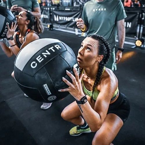 Kvinna håller en tung medicinboll under ett intensivt fitnesslopp