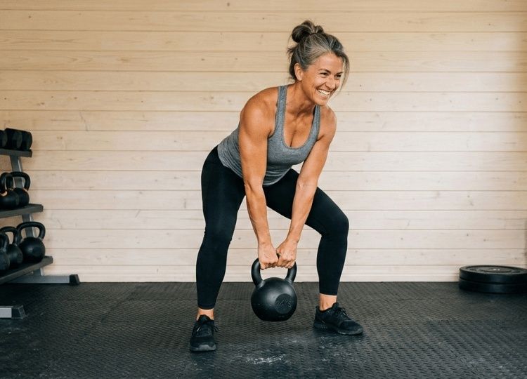 Kvinna tränar kettlebell i bred knäböjsposition på gym